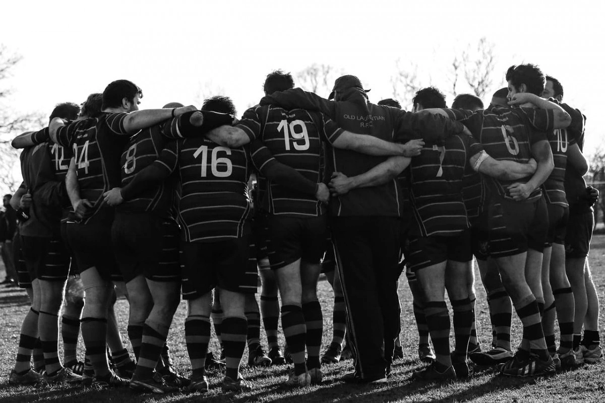 Black and white photo of a rugby team in a huddle