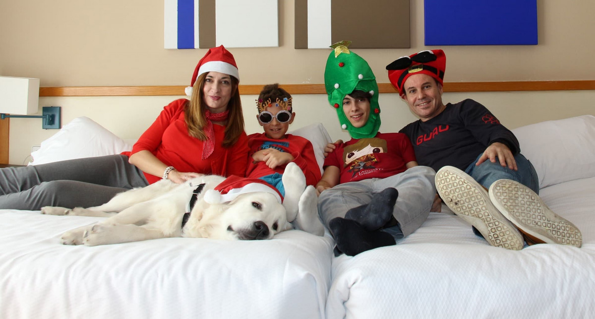 Family led on a bed wearing Christmas hats