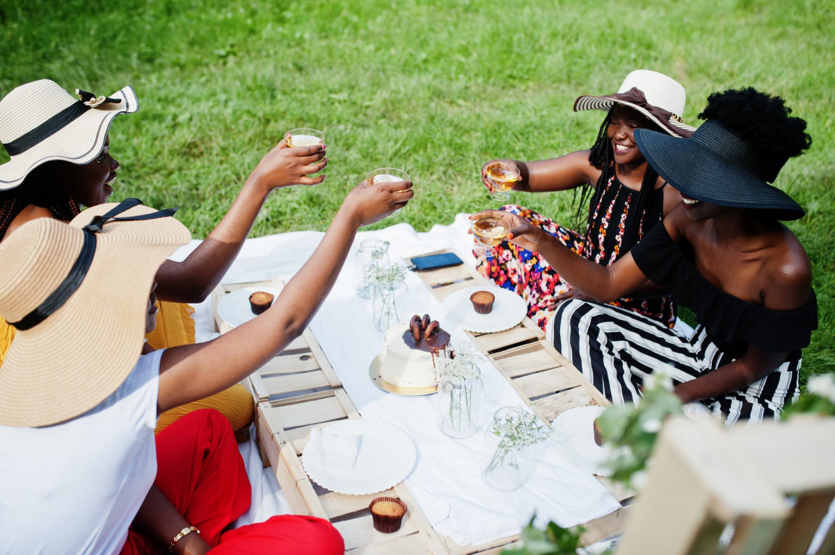 Four ladies sat around a picnic blanket raising a toast