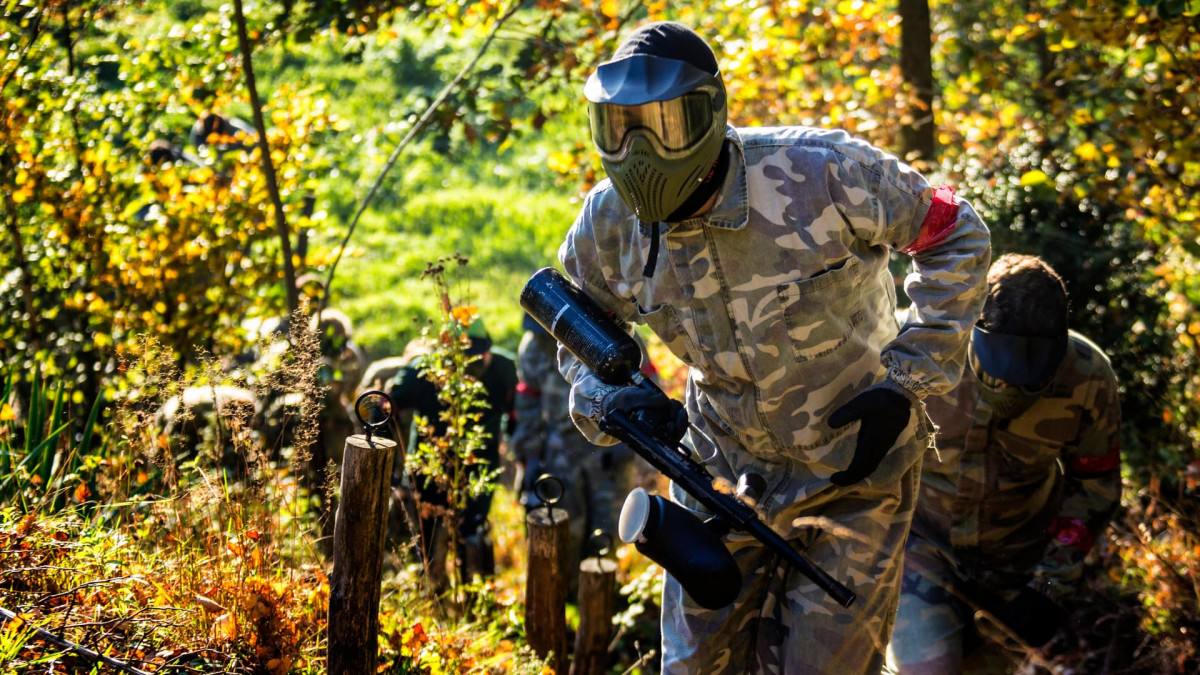 People wearing camouflage uniform while paintballing