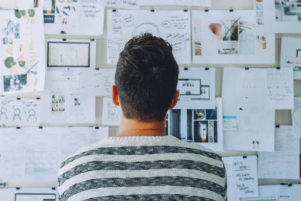 Person staring at an idea board that's full of different ideas to show that they're busy